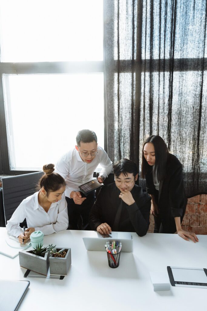Group of professionals engaged in teamwork around a laptop, discussing a project.